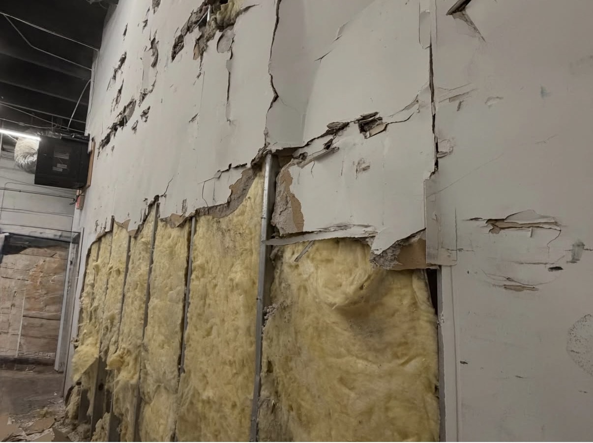 Damaged wall with exposed insulation before renovation